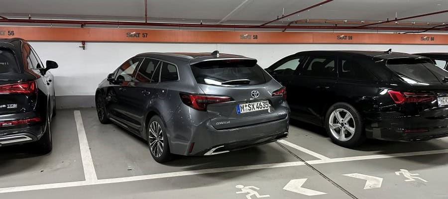 Gray Toyota Corolla station wagon parked in an indoor garage between two other vehicles, viewed from the rear three-quarter angle.