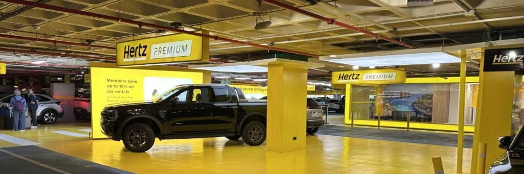 Hertz Premium rental car area with parked vehicles in a brightly lit garage